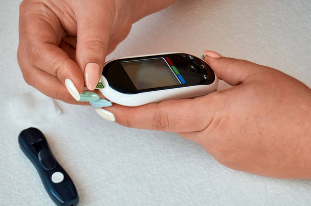 Ein Diabetiker kontrolliert seinen Blutzucker. die Frau wird zu Hause mit Lanzette und Glukometer selbst getestet. - Foto, Bild