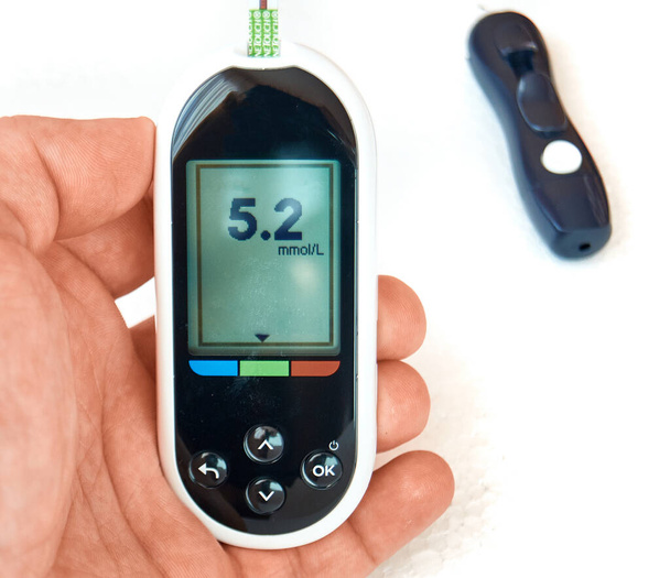Диабетик проверяет уровень сахара в крови. Женщина проходит самотестирование с Ланцетом и глюкометром дома.
. - Фото, изображение