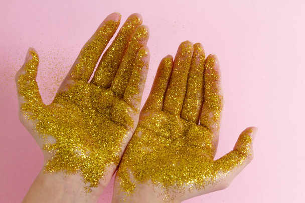 Női kezek arany csillogásban. Csillogó kezek könnyű háttéren. - Fotó, kép