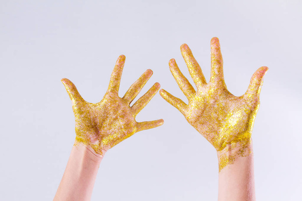 Female hands in gold sparkles. Sparkling hands on a light background. - Фото, зображення