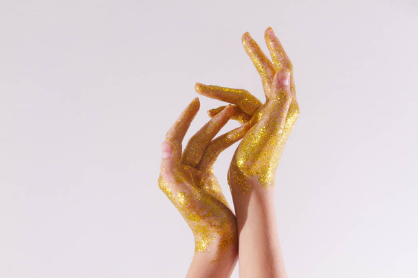 Altın parıltılı kadın elleri. Işıklı arka planda ışıl ışıl eller. - Fotoğraf, Görsel
