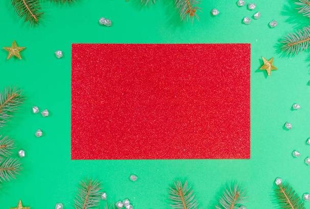 Red shiny sheet of paper and christmas tree branches on neo mint background. Christmas concept. Happy New Year 2020! Festive background. - Photo, Image