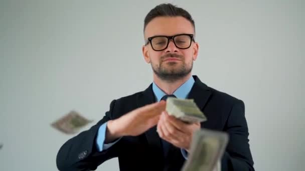 Formeel geklede man strooit dollarbiljetten om zich heen, waardoor geld gaat regenen. - Video