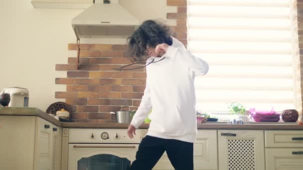 happy handsome teenager boy with long curly hair dancing in the kitchen. - Záběry, video