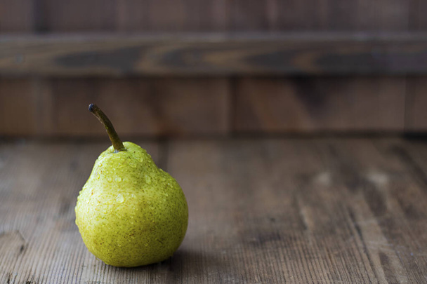fresh green pear on textured wooden brown table. Selective focus. Horizontal with copy space. For design about agricilture, fruit and healthy food - Фото, изображение