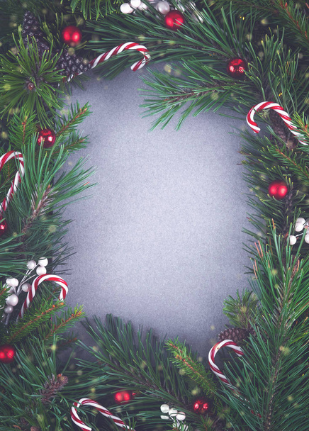 テキスト用のコピースペースを持つトーンクリスマスや新年の背景。休日の概念。エコ再生紙の空白の灰色のカードとモミの枝や装飾で作られた創造的なレイアウト。トップ表示 - 写真・画像