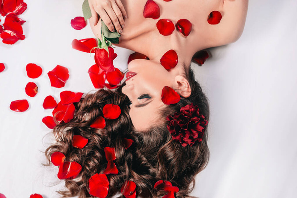 young woman with rose lying among rose petals - Fotografie, Obrázek