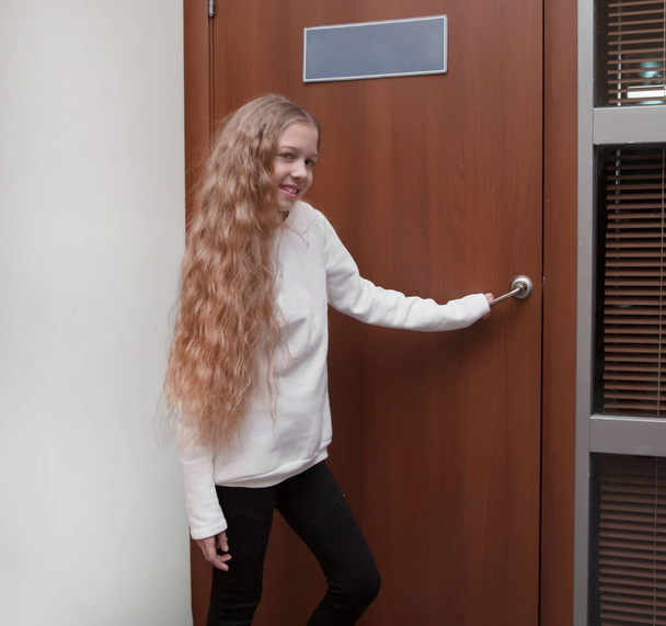 schoolgirl opening the door to the principals office - Foto, afbeelding