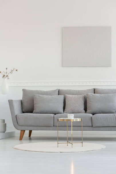 Small elegant coffee table in front of long scandinavian couch in bright daily room interior - Fotoğraf, Görsel