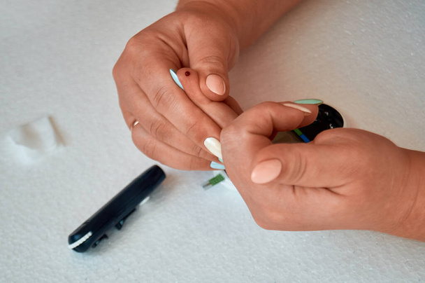 Ein Diabetiker kontrolliert seinen Blutzucker. die Frau wird zu Hause mit Lanzette und Glukometer selbst getestet. - Foto, Bild
