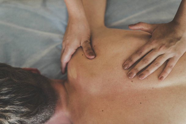 A man is given a back massage. Relaxation on the massage table. Beautiful tinted - Photo, Image