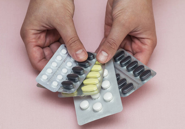 píldoras en el paquete en manos de un hombre de fondo rosa - Foto, Imagen
