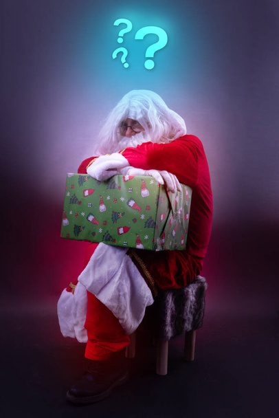 Sfrustrowany Mikołaj potrzebuje pomysłu na prezent i ma unoszące się znaki zapytania nad głową - Zdjęcie, obraz