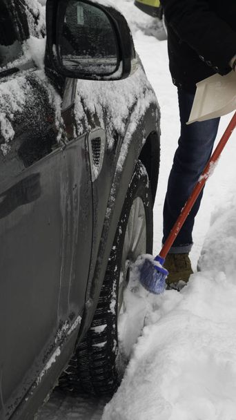  Schrapen van de sneeuw van een auto met behulp van de borstel. - Foto, afbeelding