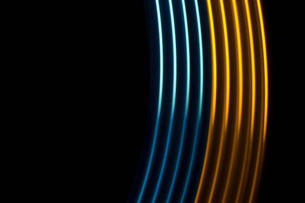 Linhas dinâmicas de luz amarela e azul em um fundo preto - Foto, Imagem
