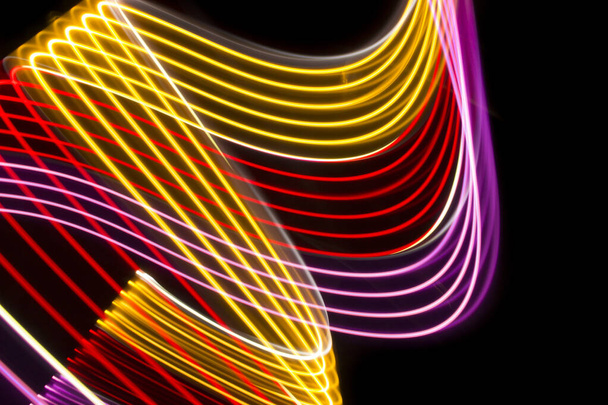 Yellow, red and pink light curve lines on a black background 	 - Foto, Imagen