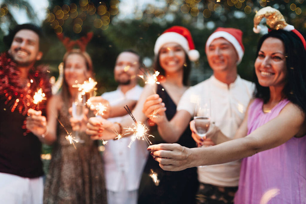 Bir grup arkadaş Noel 'i ışıltı ve şampanyayla kutluyor. - Fotoğraf, Görsel