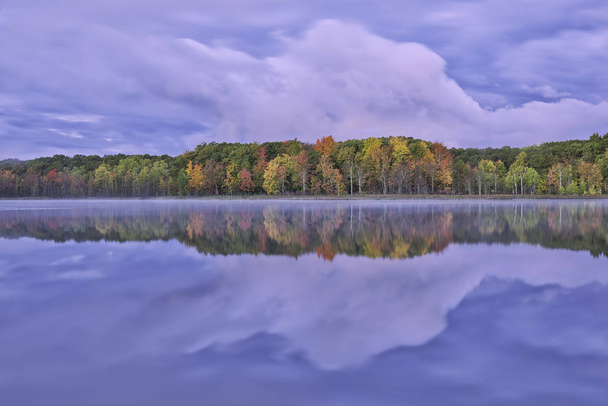 Осенний пейзаж на рассвете береговой линии Глубокого озера с зеркальными отражениями в спокойной воде, Парк штата Янки Спрингс, Мичиган, США
 - Фото, изображение