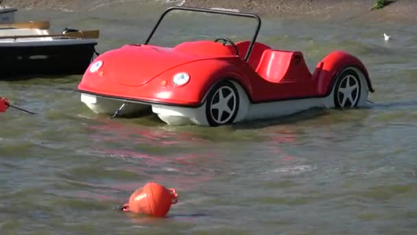 Barco rojo de plástico en forma de coches en olas de agua de mar
  - Imágenes, Vídeo