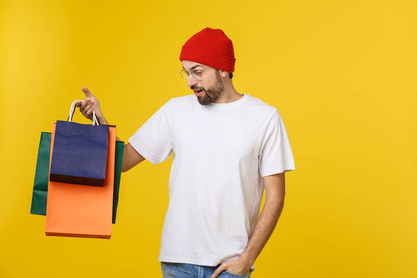 Bearded man with shopping bags with happy feeling isolated on yellow bacground - Фото, изображение