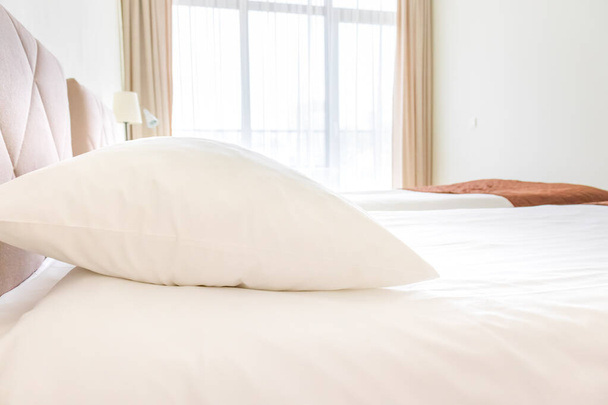 A bed with white sheets and pillows close up at a hotel appartment - Foto, imagen