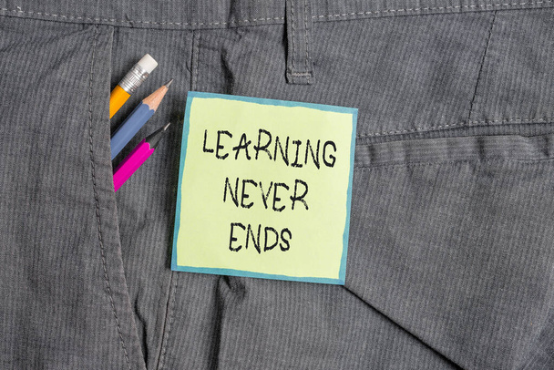 Text sign showing Learning Never Ends. Conceptual photo Life Long Educational and Wellness Opportunities Writing equipment and green note paper inside pocket of man work trousers. - Photo, Image