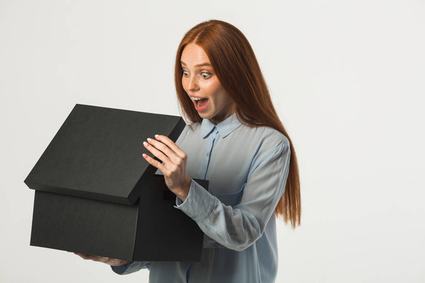 beautiful young woman with red hair with a box in her hands - Foto, imagen