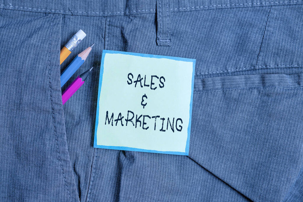 Text sign showing Sales And Marketing. Conceptual photo Promotion Selling Distribution of Goods or Services Writing equipment and green note paper inside pocket of man work trousers. - Fotoğraf, Görsel