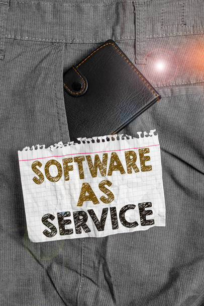 Writing note showing Software As Service. Business photo showcasing On Deanalysisd licensed on Subscription and centrally hosted Small wallet inside trouser front pocket near notation paper. - Photo, Image