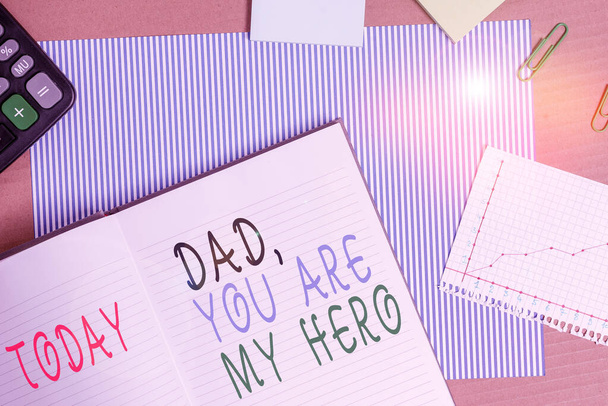 Χειρόγραφο που γράφει "Μπαμπά είσαι ο ήρωάς μου". Έννοια έννοια Θαυμασμός για τον πατέρα σου αγάπη συναισθήματα φιλοφρόνηση Ριγέ χαρτόνι σημειωματάριο γραφείο προμήθειες μελέτη χαρτί γραφήματος. - Φωτογραφία, εικόνα