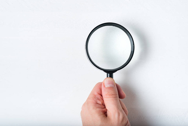 Magnifier in a man's hand on a white background. Close up - Photo, Image