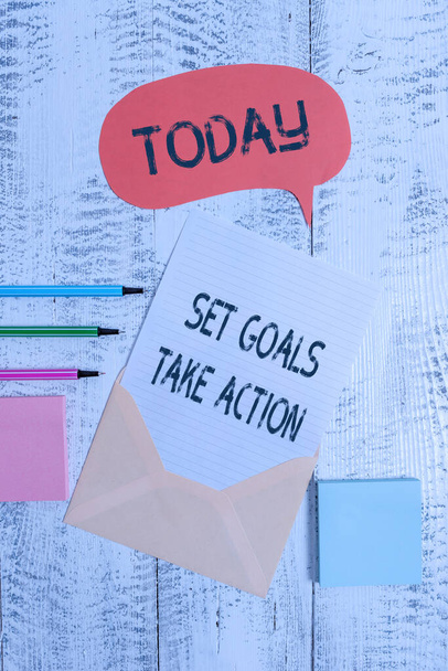 Escrevendo nota mostrando Set Goals Take Action. Foto de negócios mostrando Act em um plano específico e claramente estabelecido Envelop fala bolha folha de papel ballpoints notepads fundo de madeira
. - Foto, Imagem