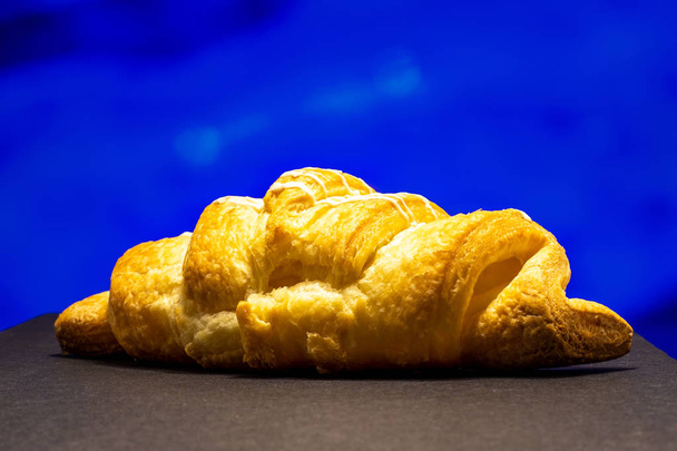 Croissant side view. Close-up on a colored background. - 写真・画像