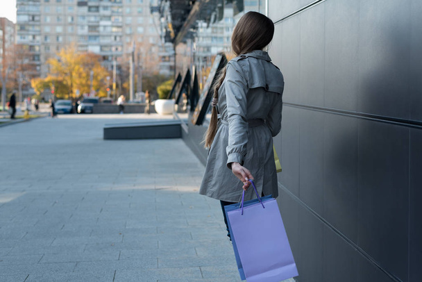 Young woman with colorful bags on the street. Mall on background - Photo, image