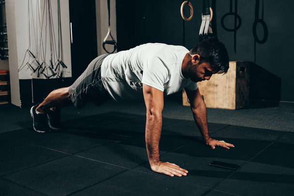 Strong man doing pushups at the gym. Calisthenics, bodyweight training - Photo, image