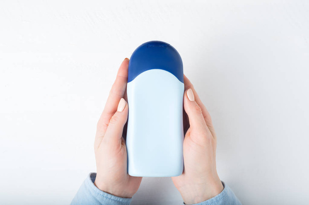 Blue bottle for cosmetic product in a female hands. White background - Zdjęcie, obraz