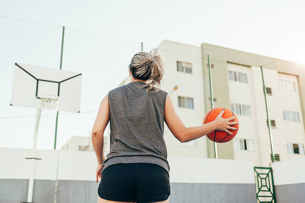 Young female basketball player training outdoors on a local court - Fotó, kép
