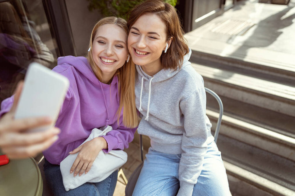 Two friendly girls doing selfie on new smartphone - Zdjęcie, obraz