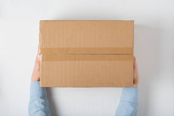 Large square cardboard box in female hands. Top view, white background - Foto, immagini