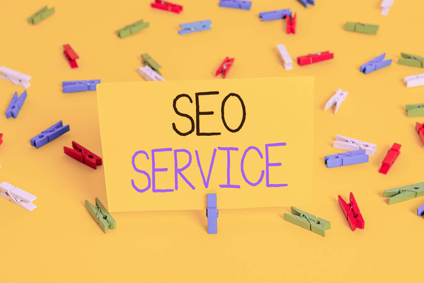 Text sign showing Seo Service. Conceptual photo techniques and procedures to increase the website visibility Colored clothespin papers empty reminder yellow floor background office. - Fotografie, Obrázek