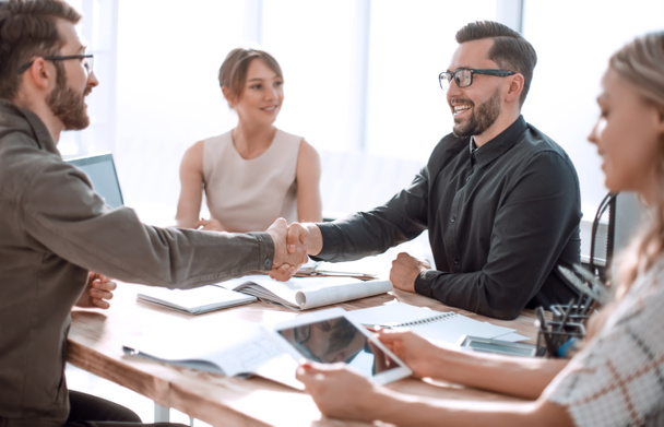 smiling business partners shaking hands at a business meeting. - Photo, Image