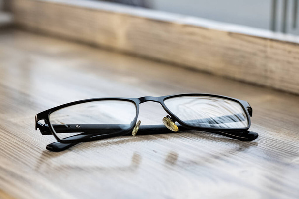 Black glasses on a wooden table closeup - Photo, Image