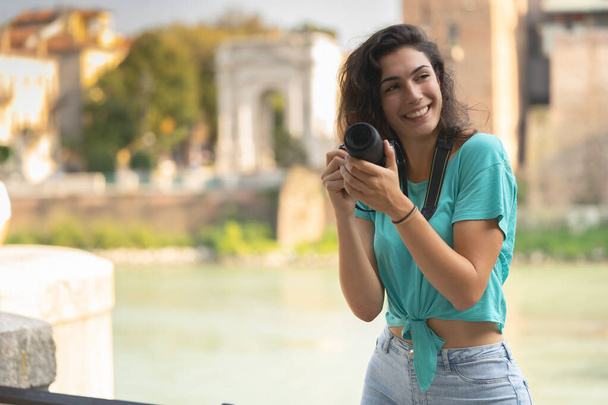 Uśmiechnięta dziewczyna we włoskim mieście z kamerą w ręku. - Zdjęcie, obraz