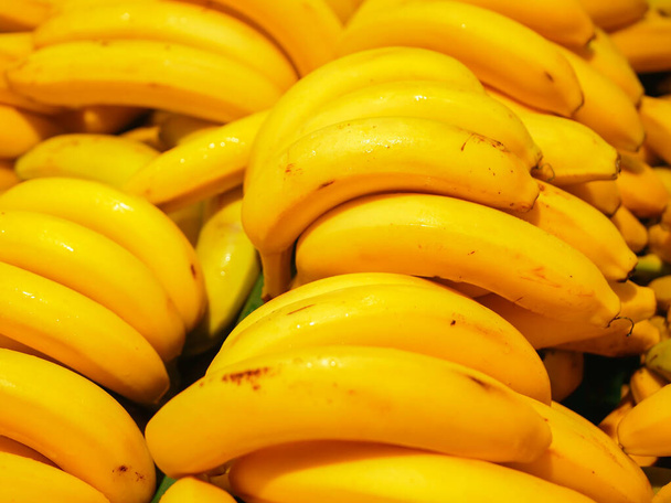 Sárga banán van a pulton. Sárga érett banán a pulton. Érett sárga banán betakarítása a piac kirakatában  - Fotó, kép