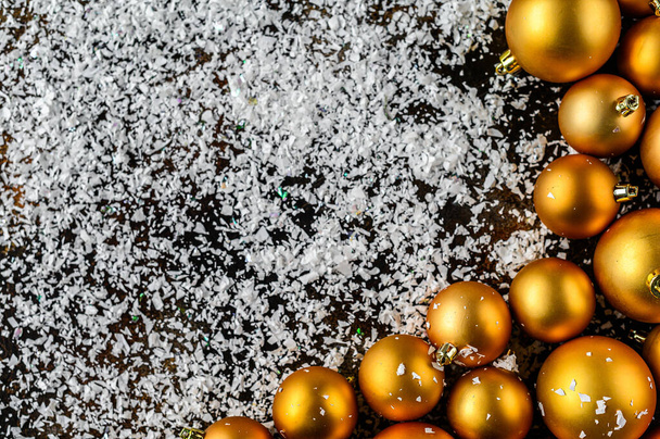 Christmas Flat Lay, new year background. Gold baubles on Dark Background, White snowflakes. Selective focus. Minimalistic design. Space for text - Foto, Imagen