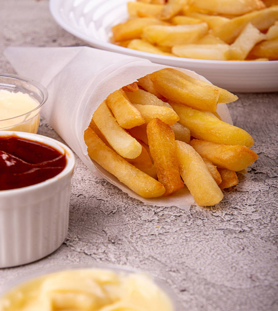 paper conus of french fries chips potato and sauces on gry concr - Foto, Bild