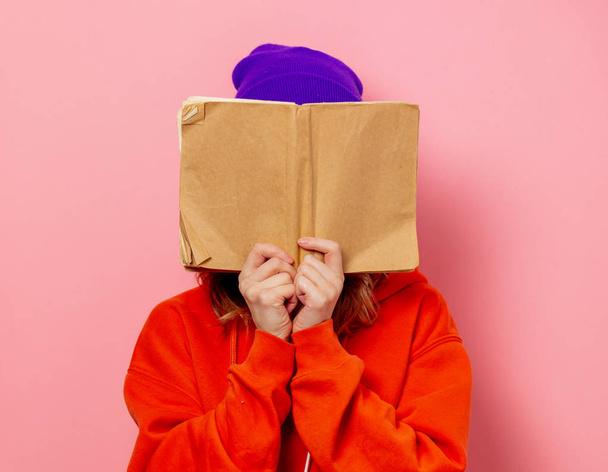 Tyyli tyttö oranssi huppari ja violetti hattu kirja vaaleanpunainen bac
 - Valokuva, kuva