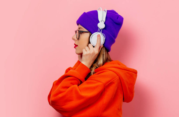 Stijl meisje in oranje hoodie en paarse hoed met hoofdtelefoon op pi - Foto, afbeelding