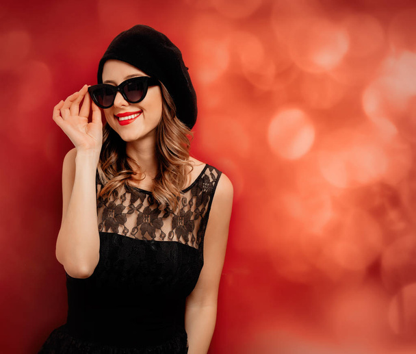 Style woman in sunglasses and black dress on red background - Photo, Image