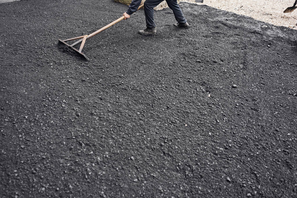 Pose d'asphalte neuf, couvrant la fosse, sur les décombres. Les travailleurs transportent des pelles et utilisent du luth d'asphalte pour obtenir de l'asphalte lisse et chaud
. - Photo, image